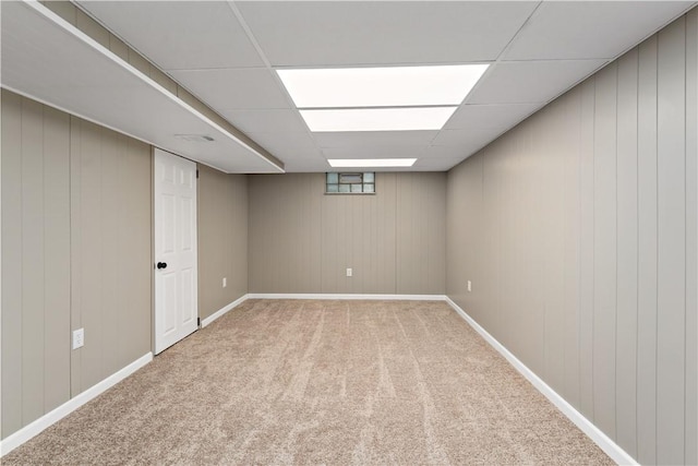 basement with a paneled ceiling and carpet