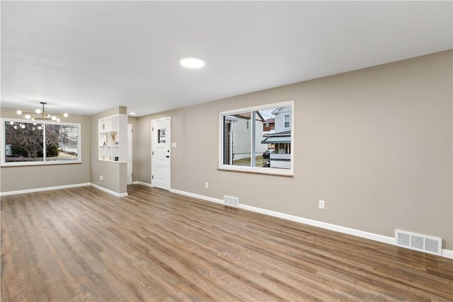 unfurnished living room featuring a chandelier and hardwood / wood-style floors