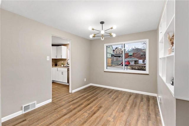 unfurnished dining area with an inviting chandelier and light hardwood / wood-style floors