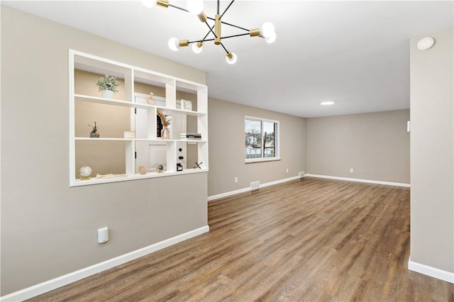 unfurnished room featuring wood-type flooring and an inviting chandelier