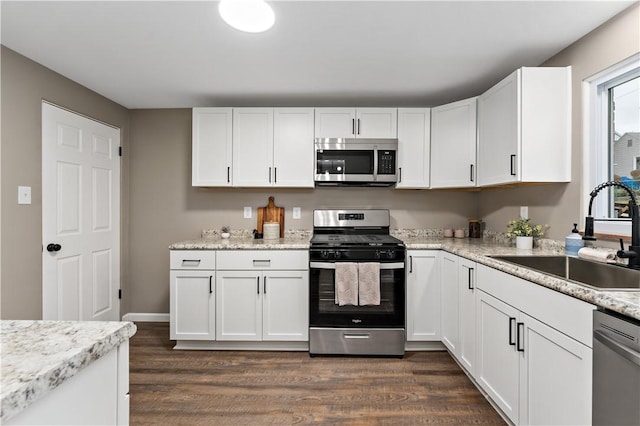 kitchen with dark wood-type flooring, appliances with stainless steel finishes, sink, and white cabinets