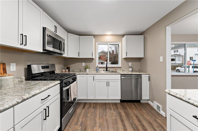 kitchen with white cabinetry, sink, light stone countertops, and appliances with stainless steel finishes