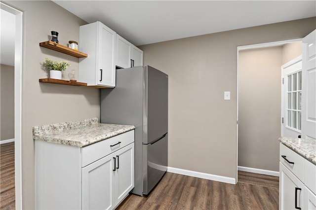 kitchen featuring stainless steel refrigerator, dark hardwood / wood-style floors, light stone counters, and white cabinets