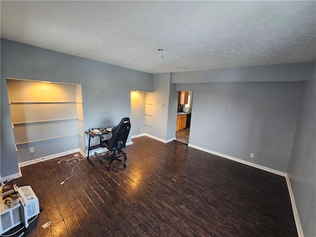 unfurnished office with dark hardwood / wood-style flooring, an AC wall unit, and a textured ceiling