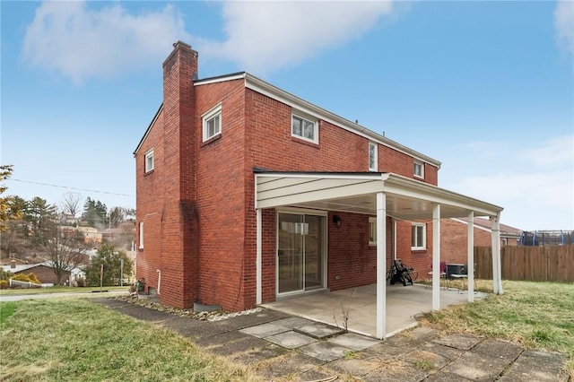 rear view of property with a lawn and a carport