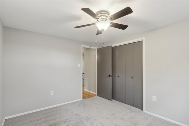 unfurnished bedroom featuring light colored carpet, ceiling fan, and a closet