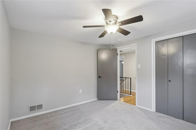 unfurnished bedroom with light colored carpet, ceiling fan, and a closet