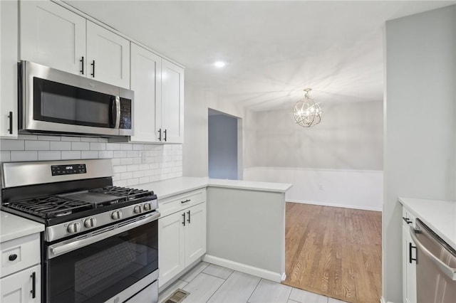 kitchen featuring tasteful backsplash, light wood-type flooring, kitchen peninsula, stainless steel appliances, and white cabinets