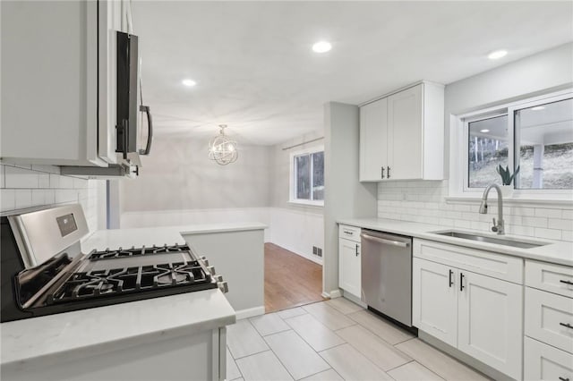 kitchen with tasteful backsplash, stainless steel appliances, sink, and white cabinets