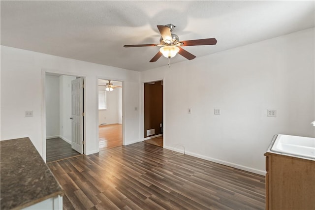 unfurnished living room with dark hardwood / wood-style flooring, sink, and ceiling fan