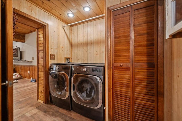 laundry room with wood-type flooring, washer and dryer, wood ceiling, and wooden walls