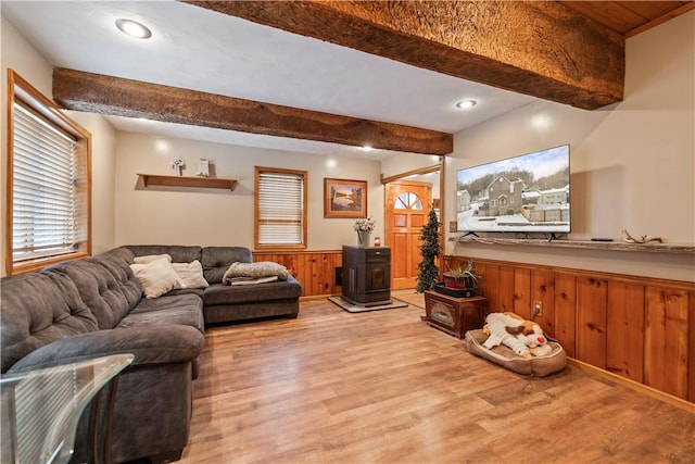 living room featuring beam ceiling, wooden walls, and light wood-type flooring