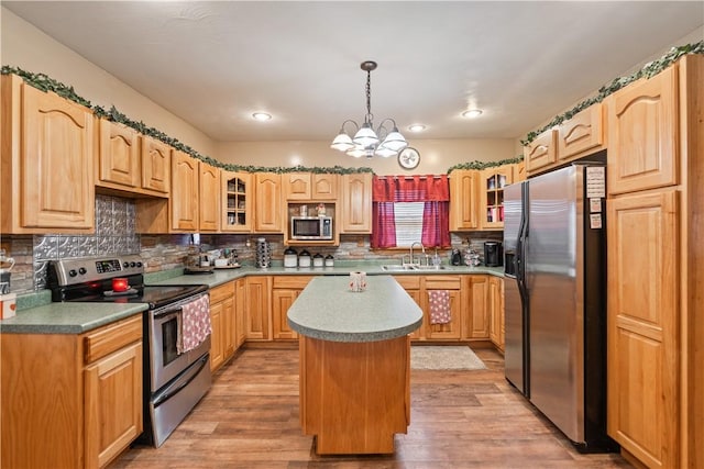 kitchen featuring sink, appliances with stainless steel finishes, hanging light fixtures, a center island, and light hardwood / wood-style floors