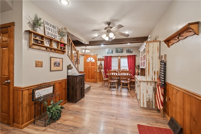 interior space featuring ceiling fan with notable chandelier, light hardwood / wood-style flooring, wooden walls, and beamed ceiling