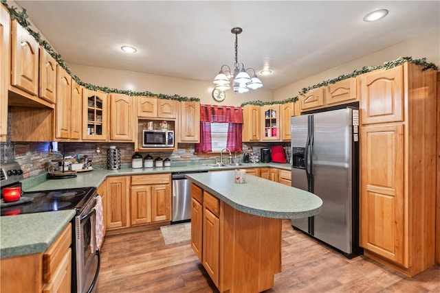 kitchen with sink, hanging light fixtures, stainless steel appliances, a center island, and light hardwood / wood-style floors