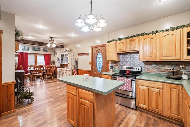 kitchen with stainless steel range with electric stovetop, decorative light fixtures, hardwood / wood-style floors, a kitchen island, and ceiling fan with notable chandelier