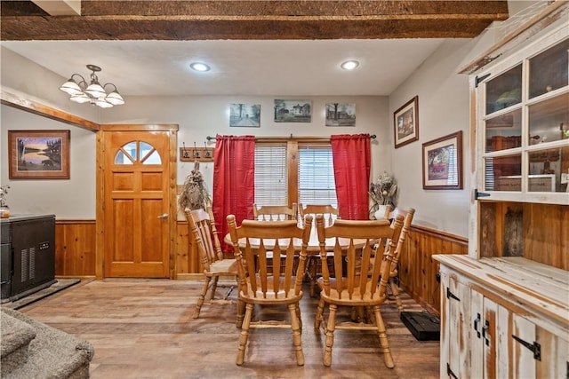 dining area with hardwood / wood-style floors, a notable chandelier, and wood walls