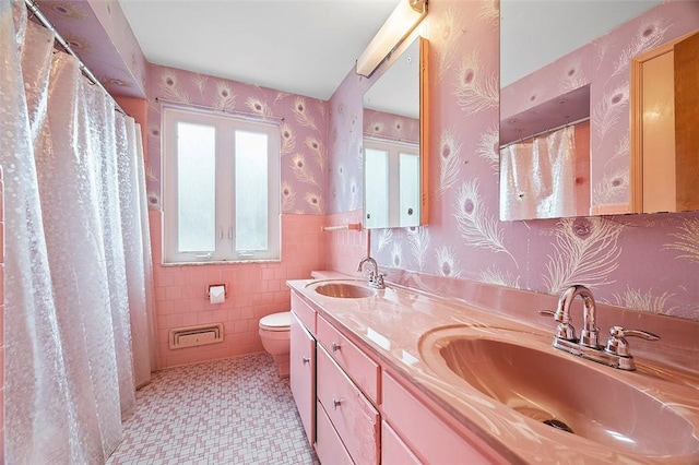 bathroom featuring vanity, toilet, curtained shower, and tile walls