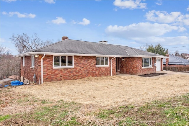 back of house with a chimney and brick siding