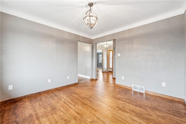 unfurnished room with a notable chandelier and hardwood / wood-style flooring