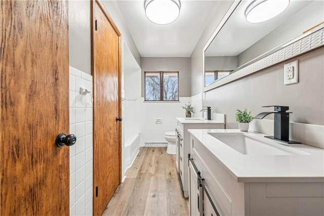 bathroom with tile walls, vanity, wood-type flooring, and toilet