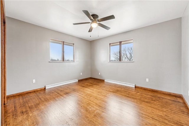 empty room featuring hardwood / wood-style floors, a wealth of natural light, and baseboard heating