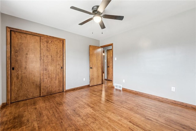 unfurnished bedroom with ceiling fan, wood-type flooring, and a closet