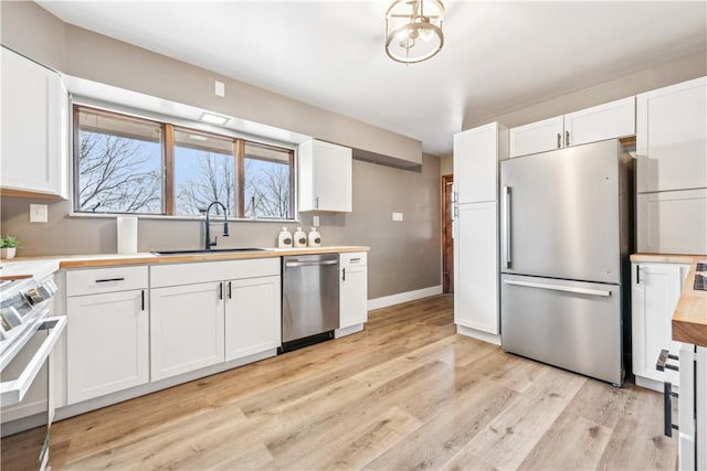 kitchen featuring white cabinetry, sink, light hardwood / wood-style floors, and appliances with stainless steel finishes