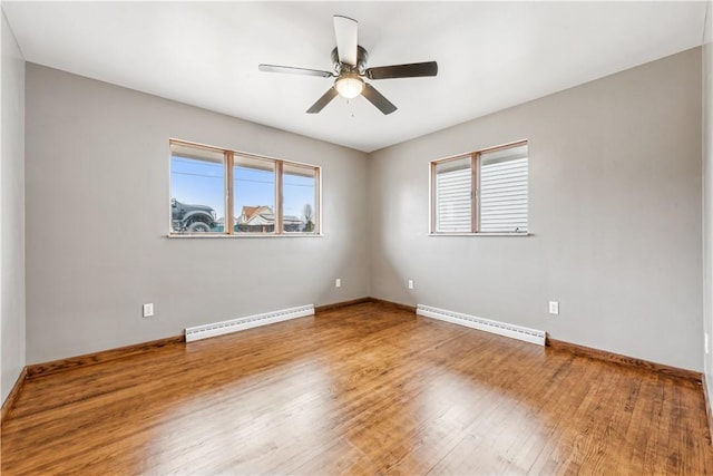 empty room featuring a wealth of natural light, hardwood / wood-style floors, and baseboard heating