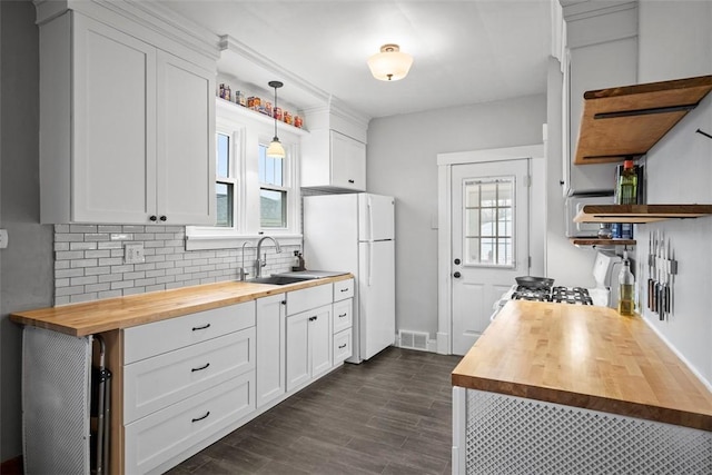 kitchen with white cabinetry, butcher block counters, sink, and decorative light fixtures