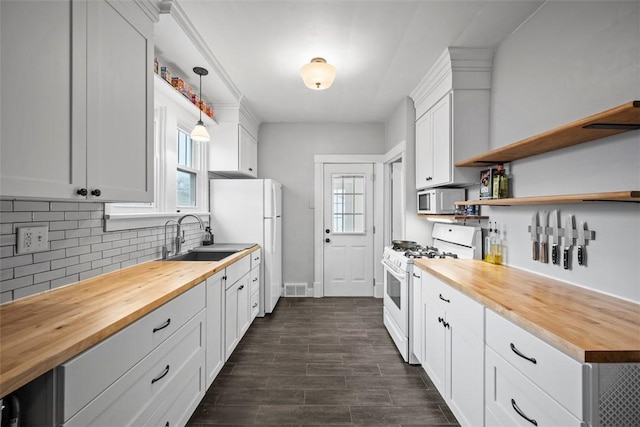 kitchen with wood counters, sink, white cabinetry, decorative light fixtures, and white appliances