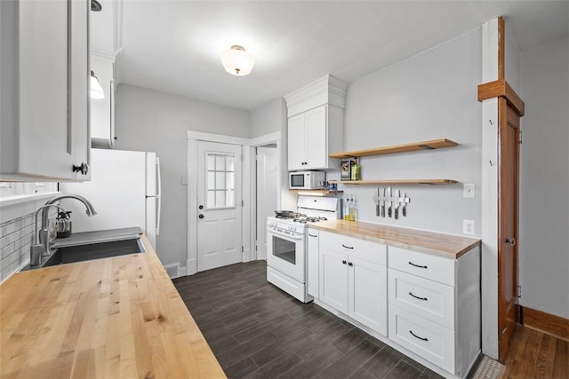 kitchen featuring white appliances, butcher block counters, sink, and white cabinets