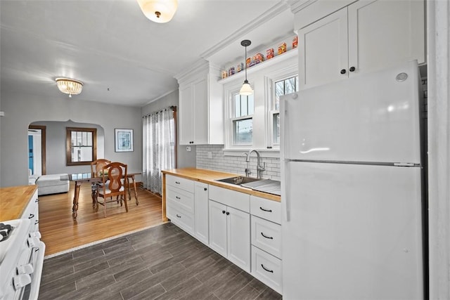 kitchen with sink, butcher block countertops, white cabinetry, hanging light fixtures, and white appliances