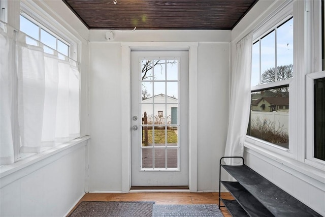 doorway featuring a healthy amount of sunlight, wooden ceiling, and light wood-type flooring