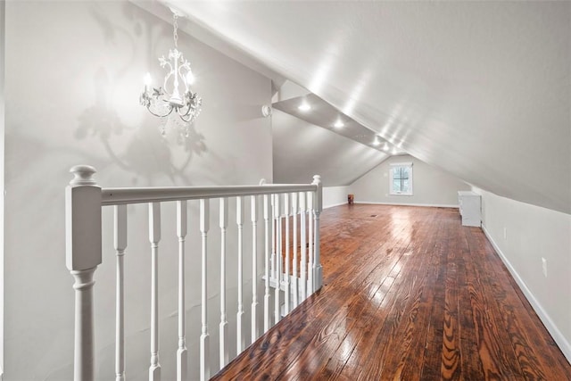 additional living space with wood-type flooring, vaulted ceiling, and a notable chandelier