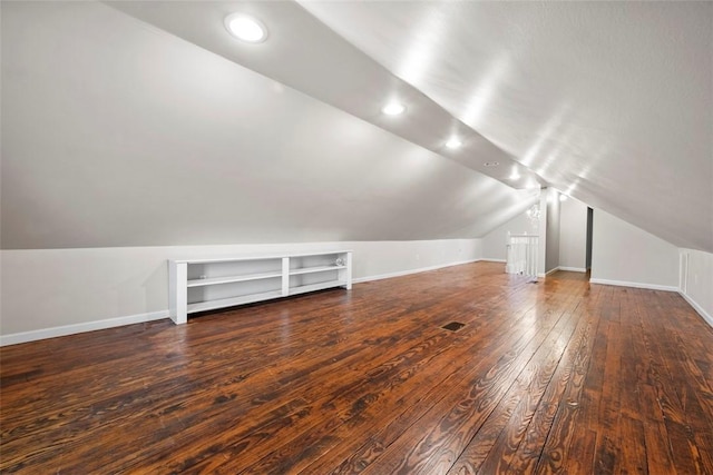 additional living space with dark hardwood / wood-style flooring, built in shelves, and lofted ceiling