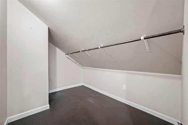 spacious closet featuring dark hardwood / wood-style floors and vaulted ceiling