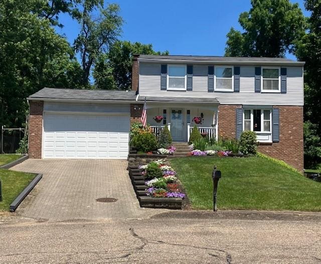 view of front of property featuring a garage, a front lawn, and covered porch