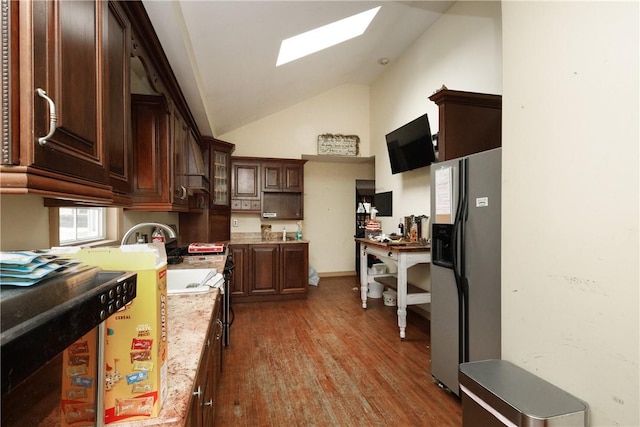 kitchen with a skylight, hardwood / wood-style flooring, dark brown cabinetry, light stone counters, and stainless steel refrigerator with ice dispenser