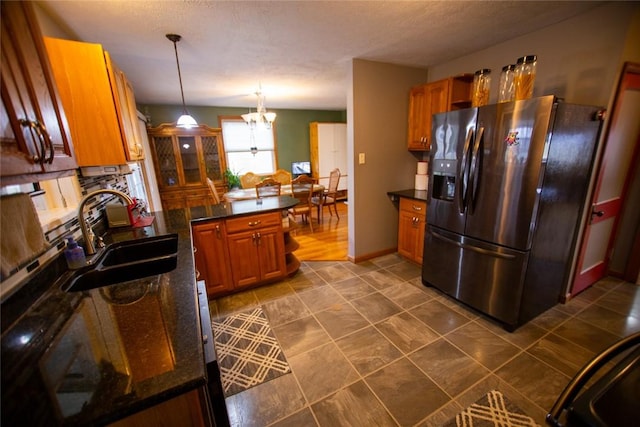 kitchen with stainless steel refrigerator with ice dispenser, sink, a textured ceiling, hanging light fixtures, and a notable chandelier