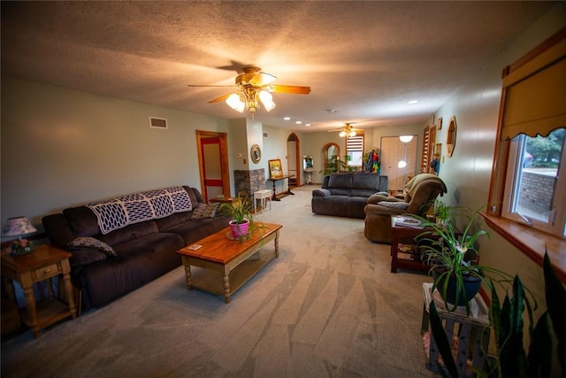 living room featuring ceiling fan, light colored carpet, and a textured ceiling