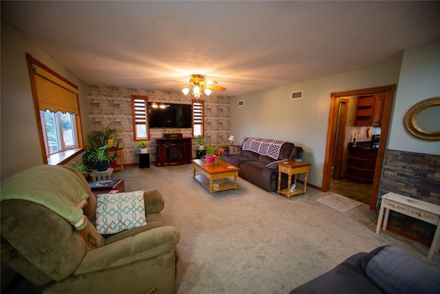 living room with ceiling fan, carpet flooring, and a textured ceiling