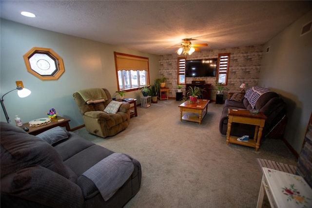 carpeted living room featuring ceiling fan and a textured ceiling