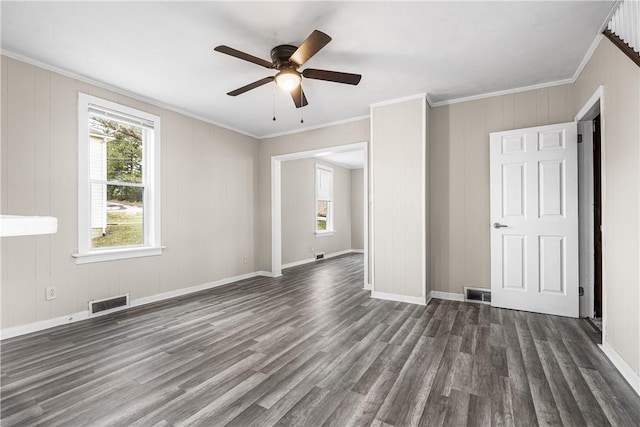 empty room featuring dark hardwood / wood-style flooring, crown molding, and plenty of natural light