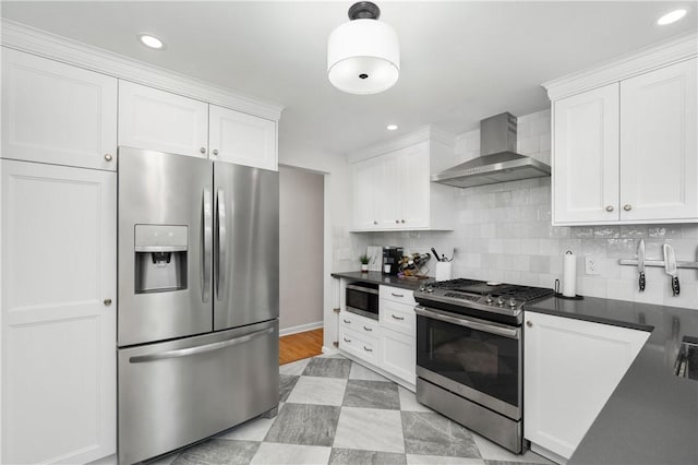 kitchen with white cabinets, appliances with stainless steel finishes, decorative backsplash, and wall chimney range hood