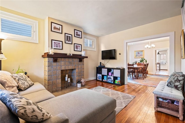 living room with a stone fireplace, wood-type flooring, and a chandelier