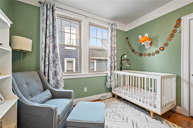 bedroom with a nursery area and hardwood / wood-style floors