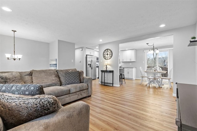 living room featuring a textured ceiling, light hardwood / wood-style flooring, and a notable chandelier