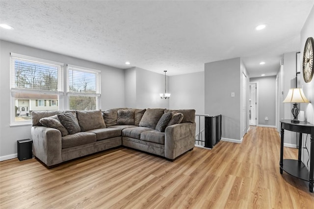 living room with an inviting chandelier, light hardwood / wood-style flooring, and a textured ceiling