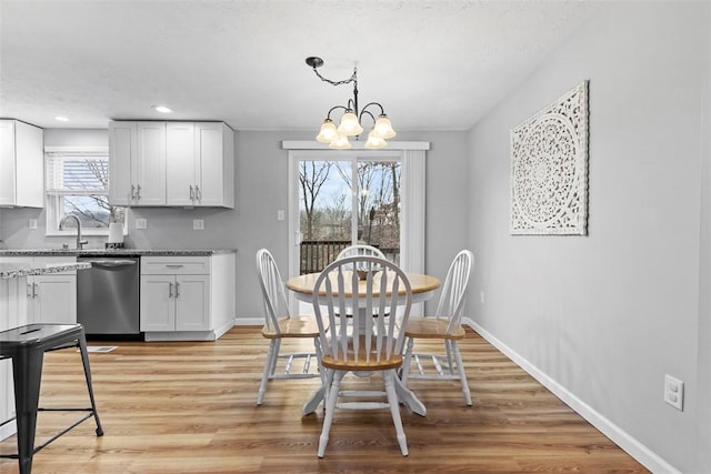 dining area featuring an inviting chandelier, sink, and light hardwood / wood-style floors